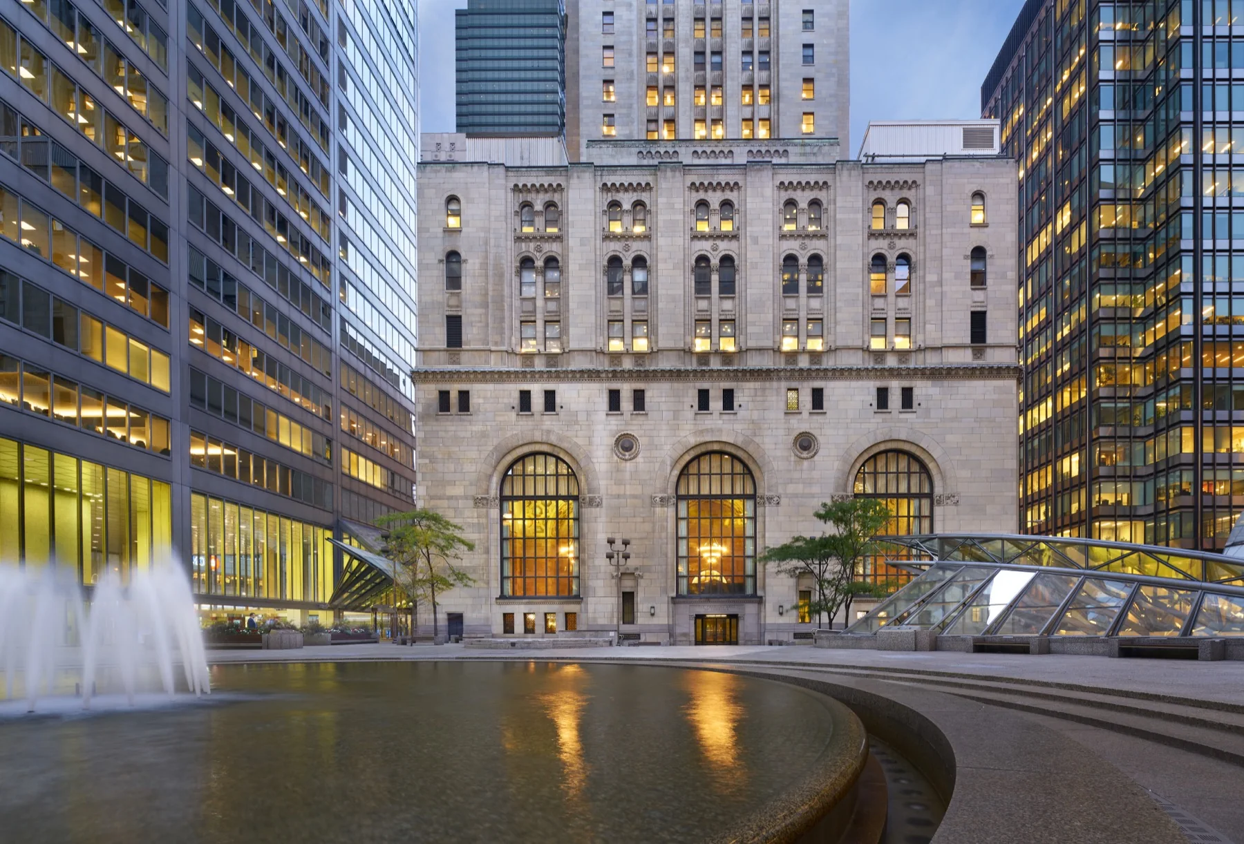 The Commerce Court courtyard in Toronto at dusk, with the historic Commerce Court North building and its reflecting pool